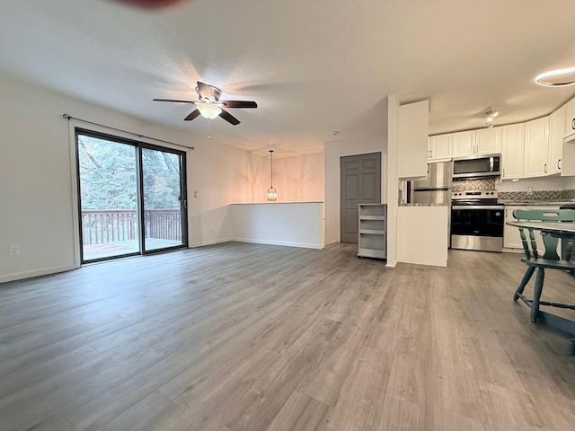 unfurnished living room featuring wood finished floors, ceiling fan, and baseboards