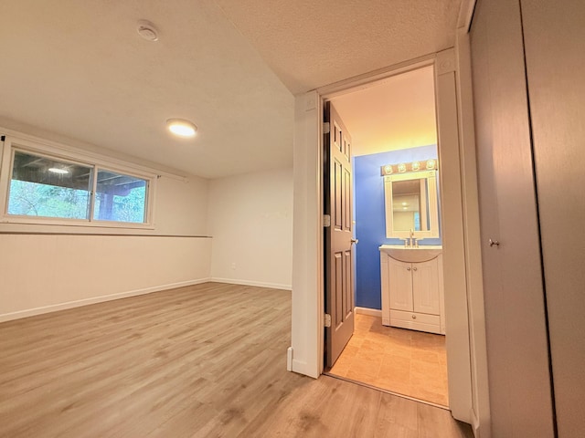 interior space with baseboards, ensuite bath, light wood-style flooring, and a sink
