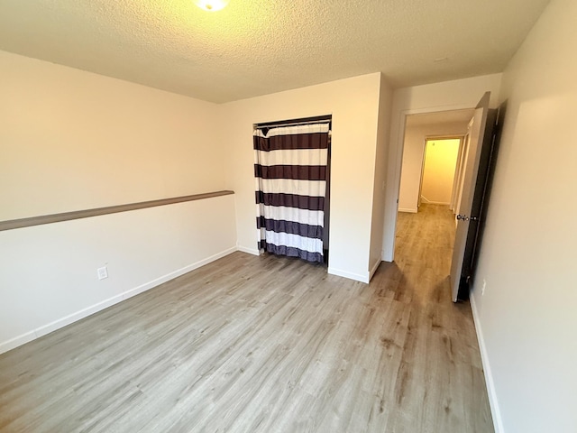 spare room featuring a textured ceiling, wood finished floors, and baseboards