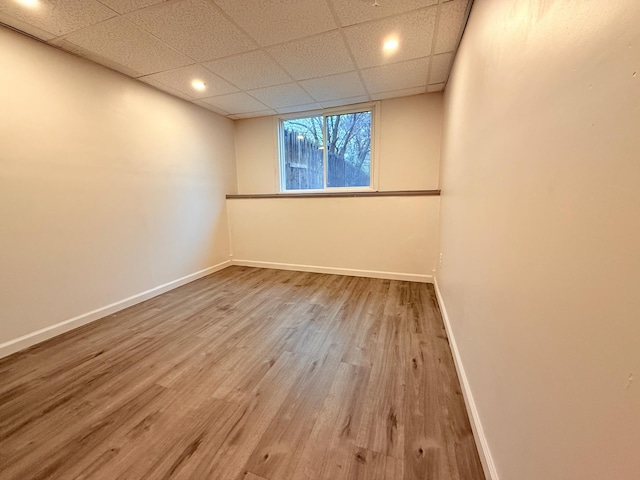 unfurnished room with baseboards, recessed lighting, wood finished floors, and a drop ceiling