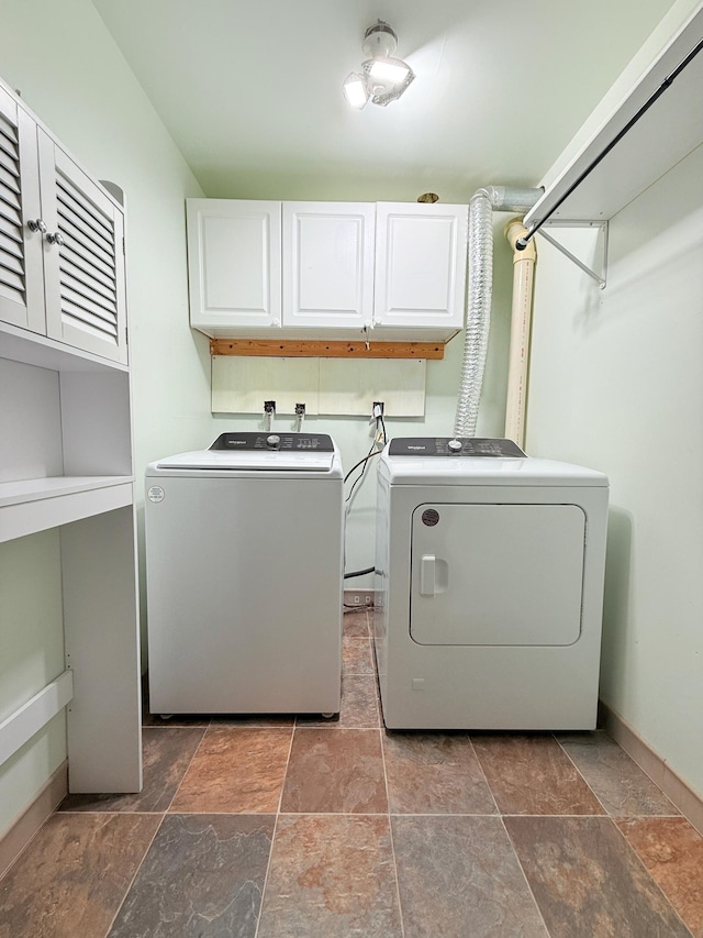 washroom with stone finish flooring, cabinet space, independent washer and dryer, and baseboards