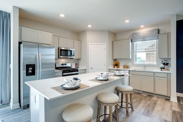 17240 Durham Dr, Lakeville, MN 55044 - kitchen with a kitchen island, a breakfast bar area, a sink, light wood-style flooring, and stainless steel appliances