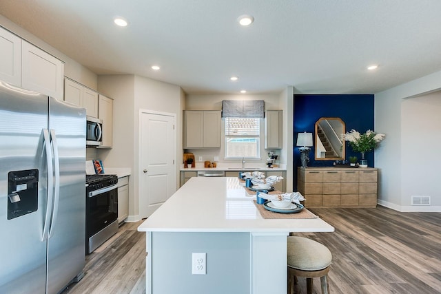 17240 Durham Dr, Lakeville, MN 55044 - kitchen with appliances with stainless steel finishes, a breakfast bar, light wood finished floors, a center island, and visible vents
