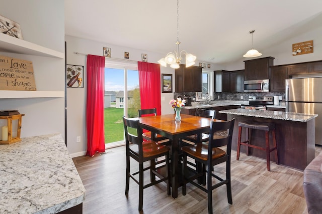 dining space featuring baseboards, an inviting chandelier, and light wood-style flooring
