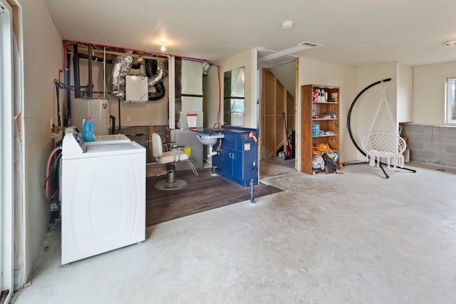 basement with water heater, washing machine and dryer, and visible vents
