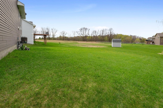 view of yard with central air condition unit, an outbuilding, and a shed