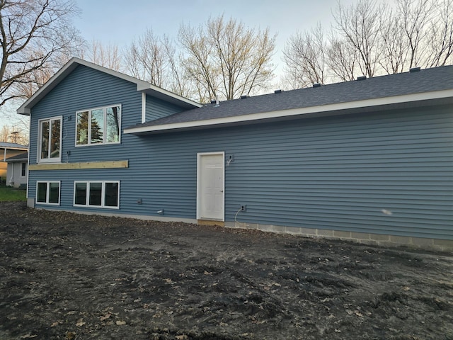rear view of house featuring roof with shingles