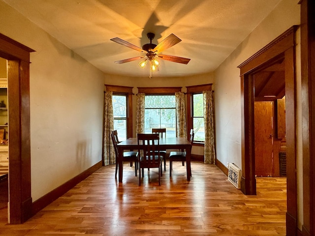 dining area featuring a ceiling fan, baseboards, visible vents, and wood finished floors