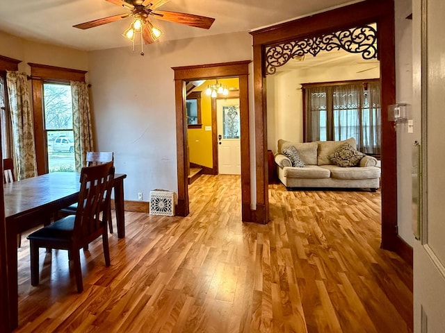 dining space with baseboards, ceiling fan with notable chandelier, and wood finished floors