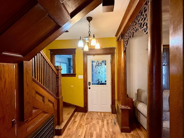 foyer featuring visible vents, light wood-type flooring, stairs, and a notable chandelier
