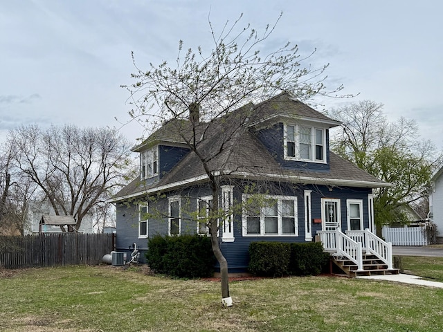 view of front of home featuring central air condition unit, fence, and a front yard