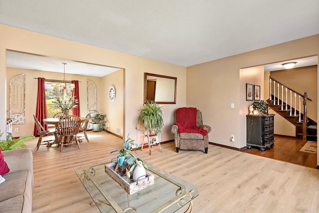 living room with baseboards, stairs, wood finished floors, and a notable chandelier