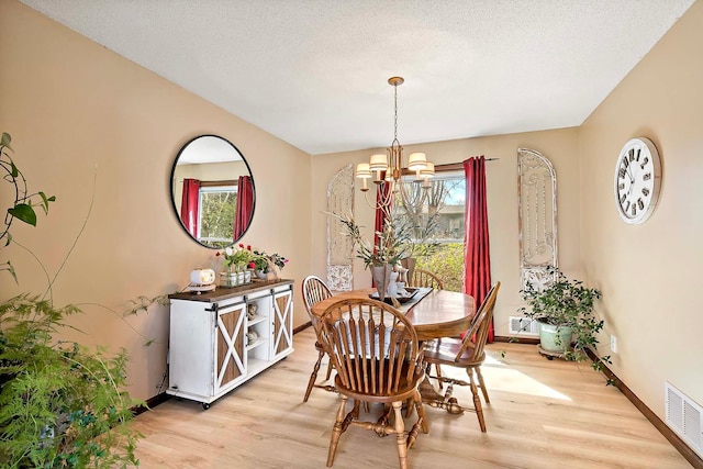 dining room with baseboards, a chandelier, visible vents, and light wood-style floors