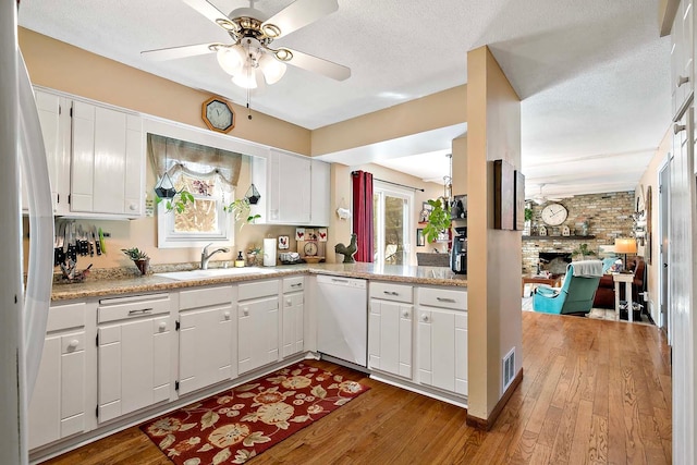 kitchen with a brick fireplace, wood finished floors, white appliances, ceiling fan, and a sink