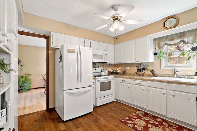 kitchen featuring white cabinets, a sink, white appliances, dark wood finished floors, and a ceiling fan