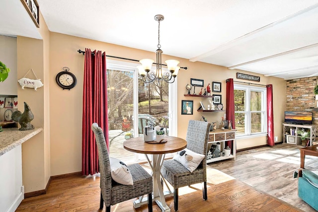 dining space featuring baseboards, a notable chandelier, and light wood finished floors