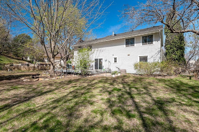 back of house featuring a lawn and fence