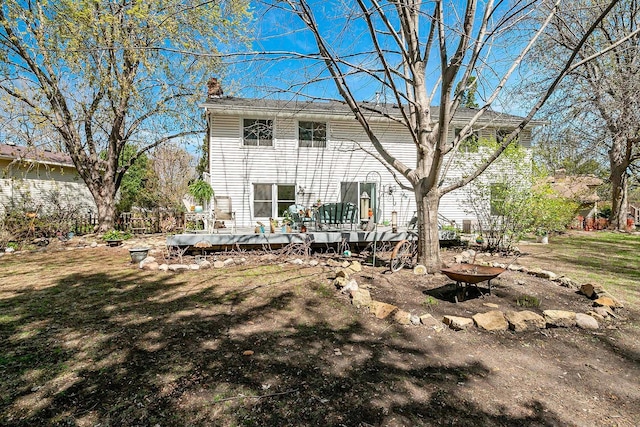 back of property featuring a wooden deck, a chimney, and a yard