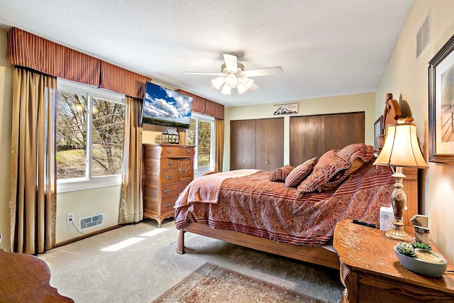 carpeted bedroom featuring visible vents, a textured ceiling, baseboards, and ceiling fan