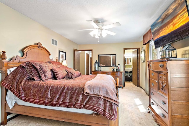 bedroom with light colored carpet, a ceiling fan, visible vents, and ensuite bath