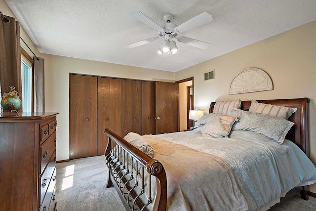 bedroom with visible vents, ceiling fan, a closet, and light colored carpet