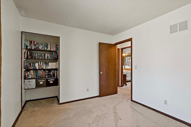 spare room featuring visible vents, carpet, and baseboards