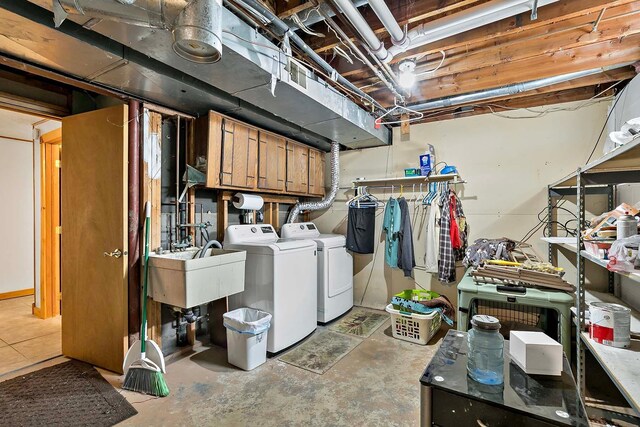 clothes washing area featuring cabinet space, washing machine and dryer, and a sink