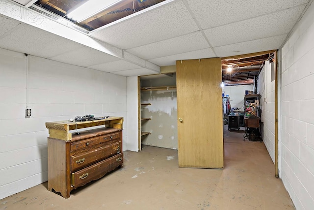 unfinished below grade area featuring concrete block wall and a drop ceiling