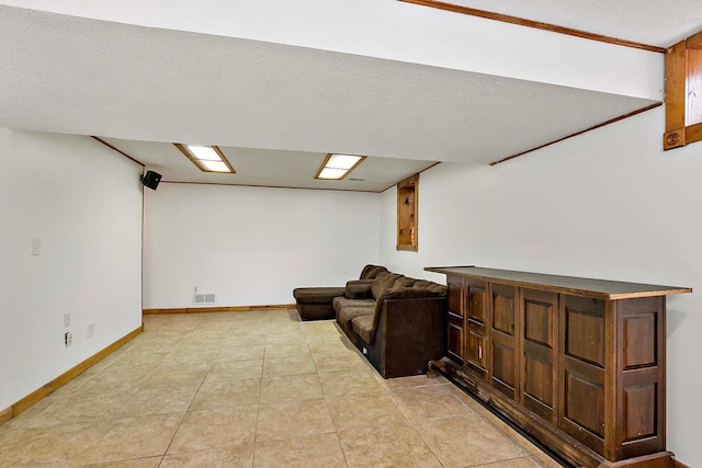 interior space featuring light tile patterned floors, a textured ceiling, visible vents, and baseboards