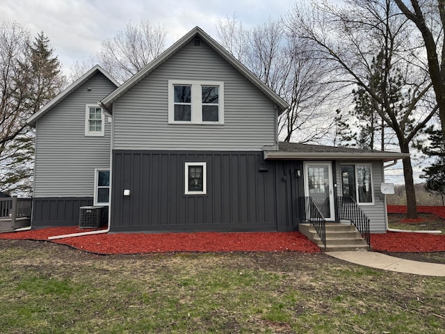 back of property featuring a lawn, board and batten siding, entry steps, and cooling unit