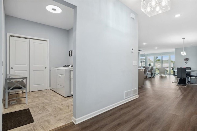 corridor featuring washing machine and dryer, visible vents, baseboards, recessed lighting, and wood finished floors