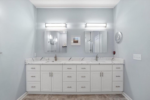 full bath featuring baseboards, double vanity, and a sink