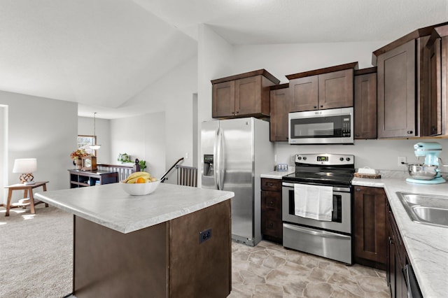 kitchen with a center island, dark brown cabinetry, light countertops, appliances with stainless steel finishes, and lofted ceiling