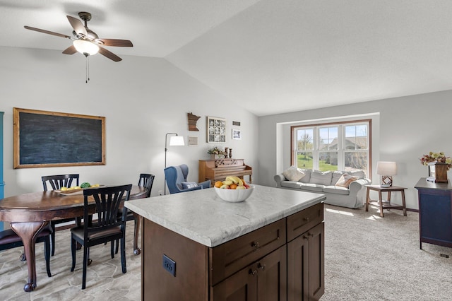 kitchen with vaulted ceiling, dark brown cabinets, ceiling fan, light countertops, and a kitchen island