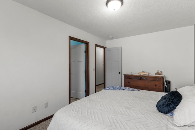 bedroom with a textured ceiling, carpet flooring, and baseboards