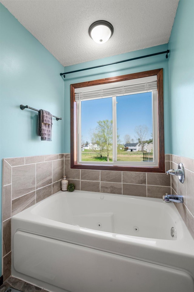 bathroom with a tub with jets and a textured ceiling