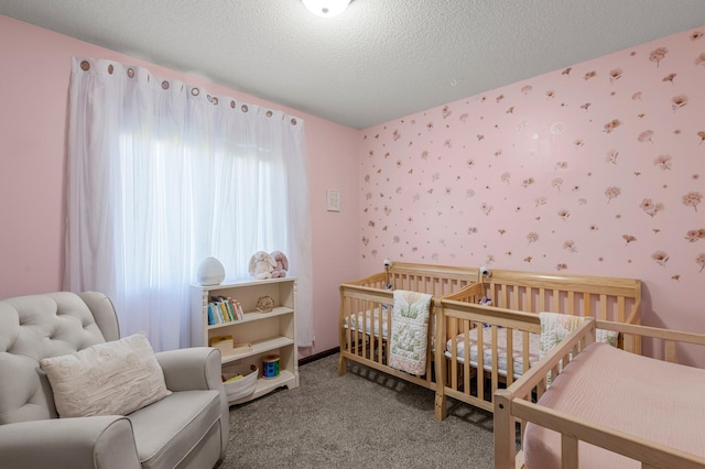 bedroom featuring carpet flooring, a nursery area, a textured ceiling, and wallpapered walls