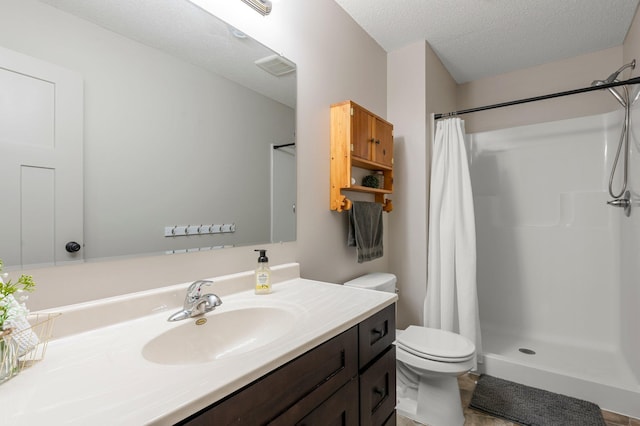 bathroom featuring vanity, toilet, a stall shower, and a textured ceiling