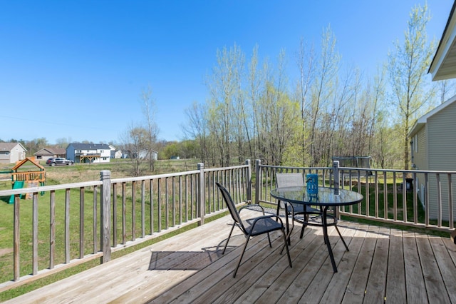 deck with a yard, outdoor dining space, and a playground
