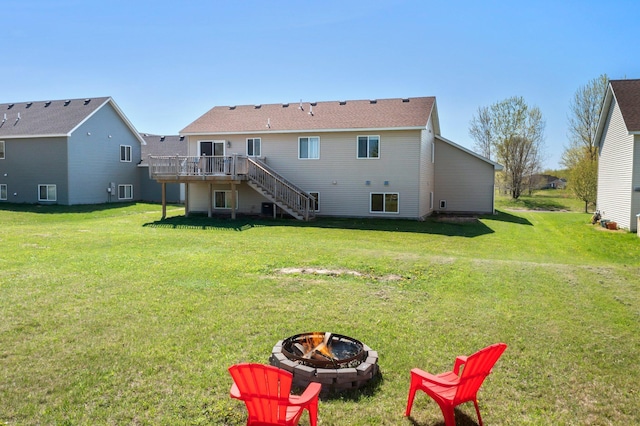 rear view of house featuring a yard, stairs, a wooden deck, and a fire pit