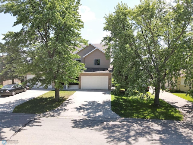 view of property hidden behind natural elements with an attached garage and concrete driveway