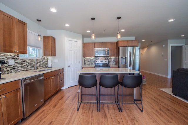 kitchen with decorative backsplash, a kitchen bar, a sink, stainless steel appliances, and light wood-style flooring