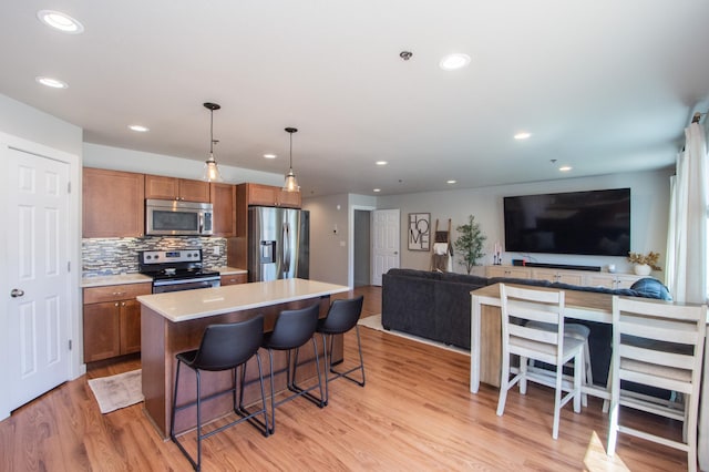 kitchen featuring light wood-style floors, stainless steel appliances, brown cabinets, and a kitchen bar