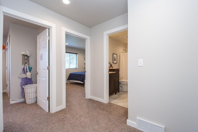 corridor featuring visible vents, recessed lighting, baseboards, and light colored carpet