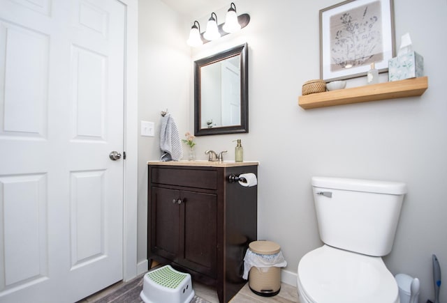 half bath with vanity, baseboards, and toilet