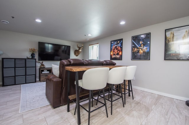 interior space featuring baseboards, a bar, and recessed lighting