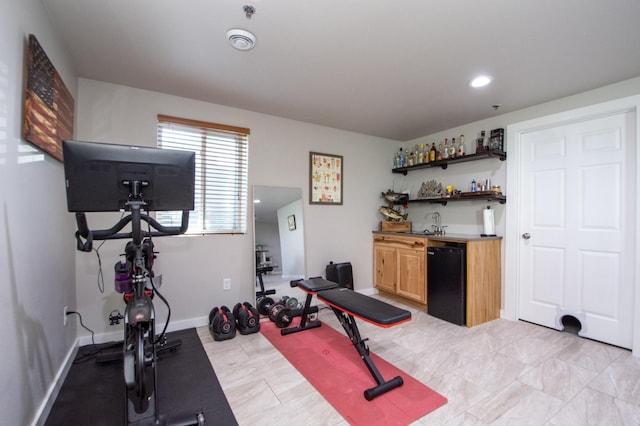 workout room featuring a sink, baseboards, recessed lighting, and wet bar