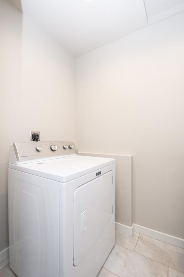 clothes washing area with washer / clothes dryer, light tile patterned flooring, laundry area, and baseboards