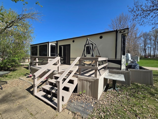 back of property with a sunroom, stucco siding, and a deck