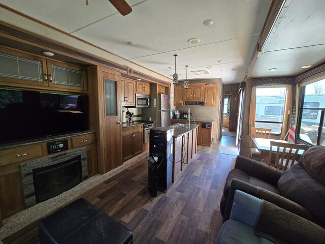 living room with a wealth of natural light, dark wood-style floors, a ceiling fan, and visible vents